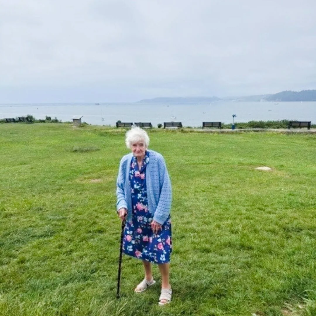 Kath standing on the grass at Jennycliff with Plymouth Sound behind her