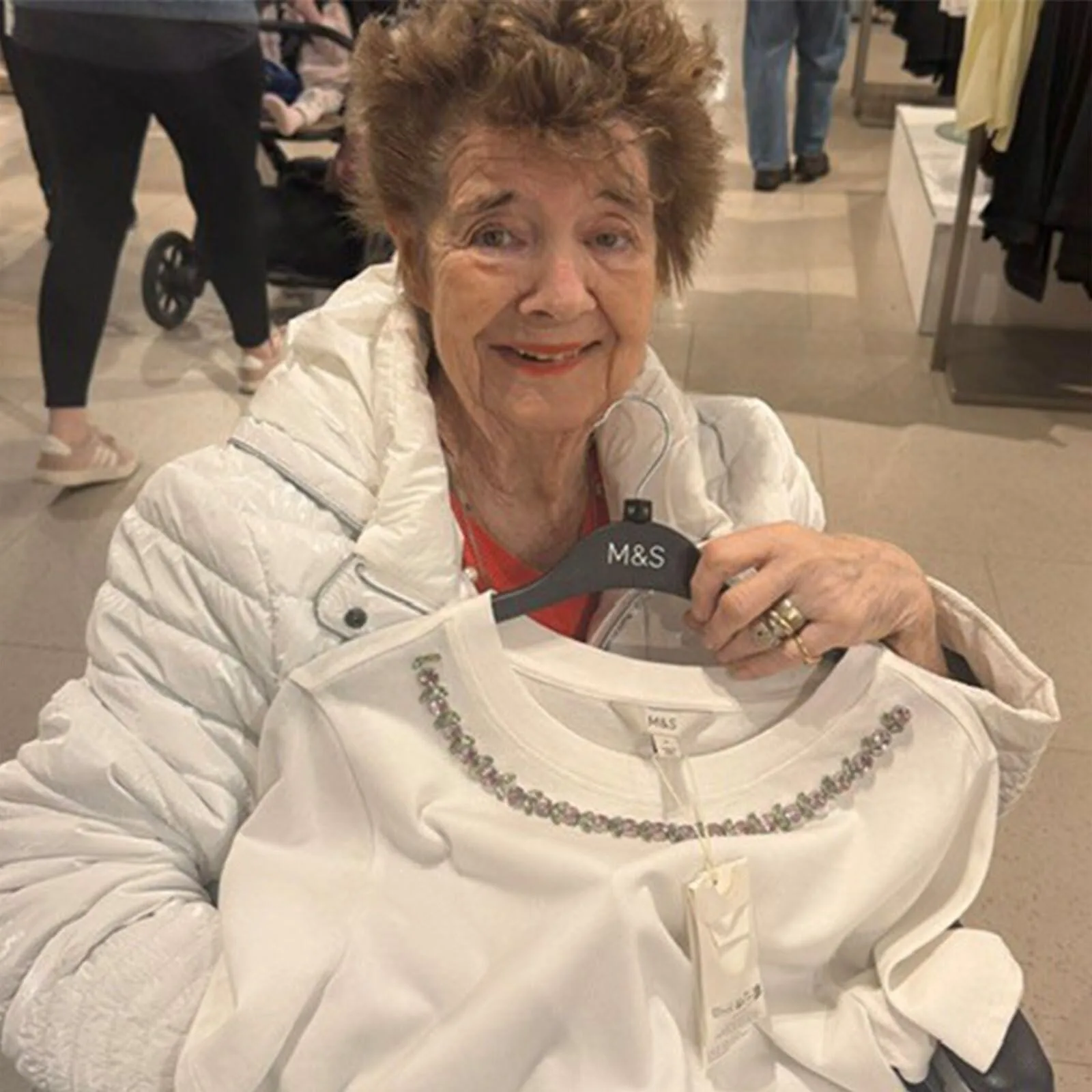 Pam smiling while holding a top during a supported shopping trip to M and S